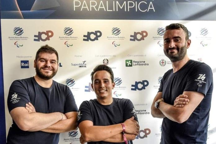 Three athletes are posing for a photo in front of a banner that says Paralimpica