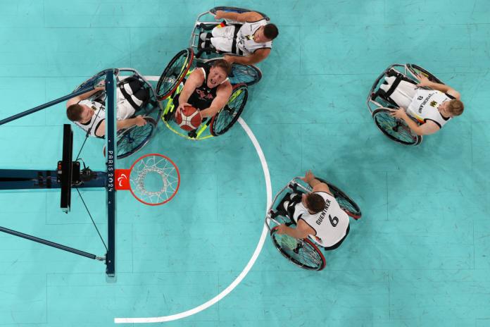An overhead photo of five wheelchair basketball players in action in front of the post