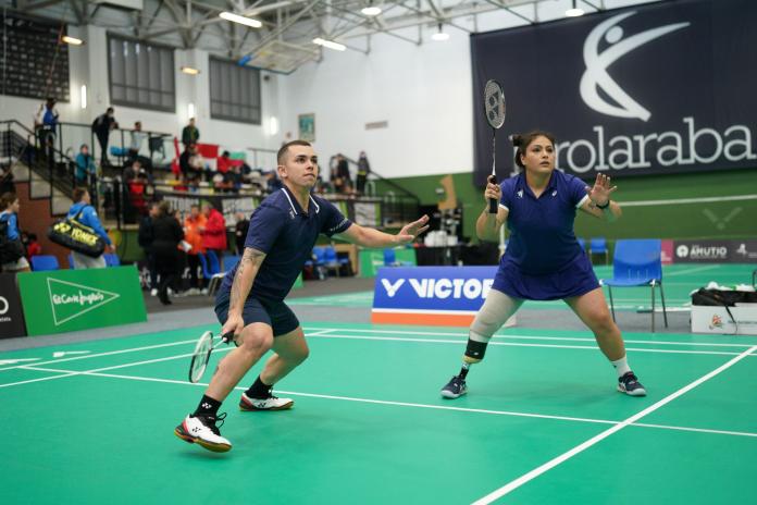 A male athlete and a female athlete compete in a mixed doubles badminton game