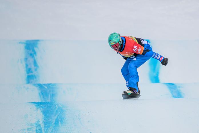 A male Para snowboard athlete is in competition.