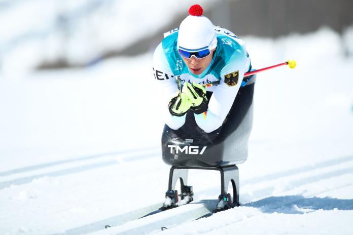 A female sit-skier is competing in a cross-country race