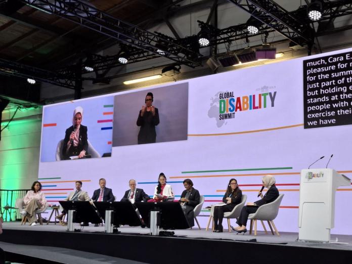Eight people taking part in a panel discussion at the Global Disability Summit