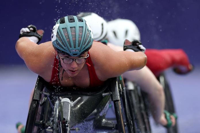 A female wheelchair racer competes on the track at Paris 2024