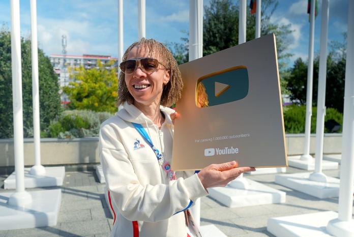A female Paralympic athlete pose for a photo while holding YouTube's golden plaque