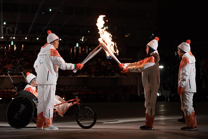 A man and a woman hold the torch and pass the flame during the PyeongChang 2018 Opening Ceremony