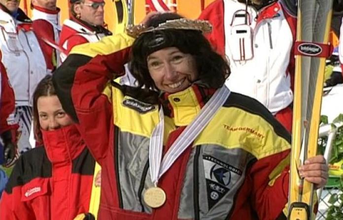 A female athlete is smiling on the podium after receiving a gold medal