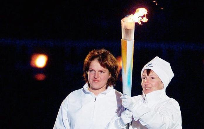Two people are holding a torch together during the Salt Lake City 2002 Opening Ceremony