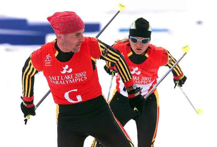 A female skier is competing behind a sighted guide