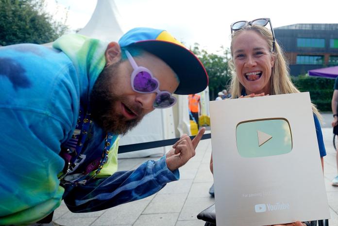 Two athletes pose for a photo while holding YouTube's golden plaque