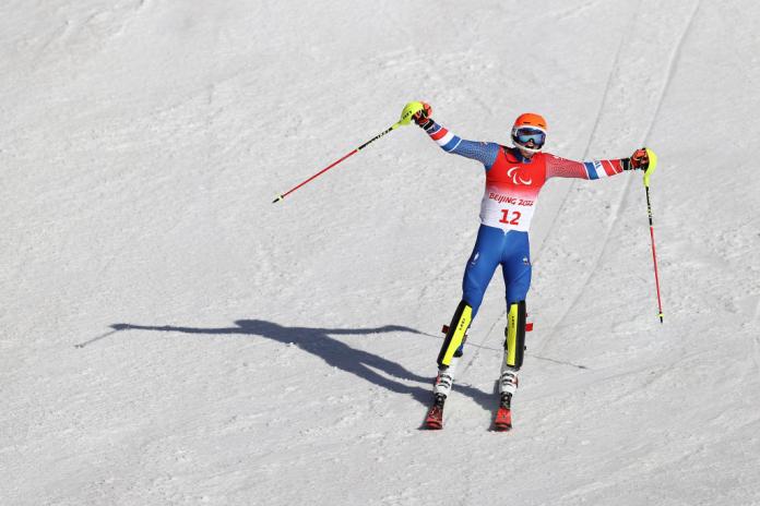 A male Para alpine skier celebrates at the finish line