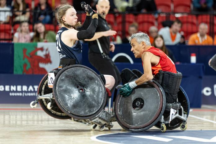 A female wheelchair rugby player collides with a male player