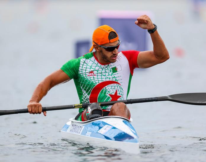 A male Para canoe athlete pumps his fist