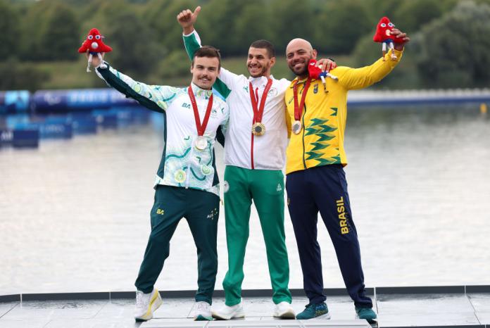 Three male athletes posing for a photograph after receiving their medals