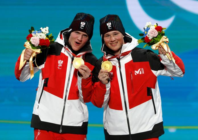 Two male athletes posing for a photo with their gold medal