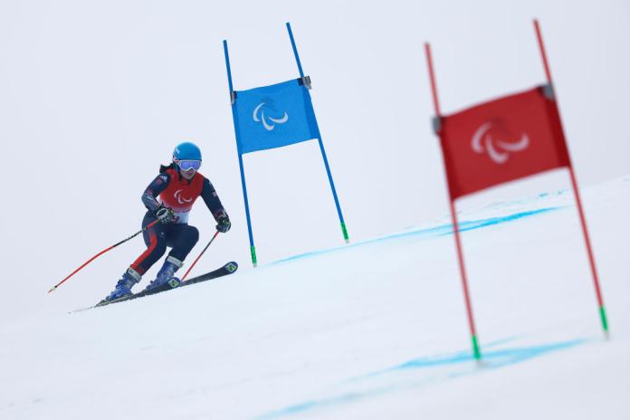 A female Para alpine skier in action between two gates.