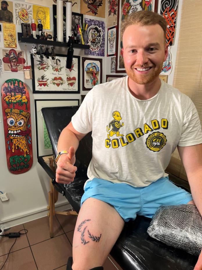 Declan Farmer poses for a photo after getting a tattoe of the Paralympic logo on his right thigh