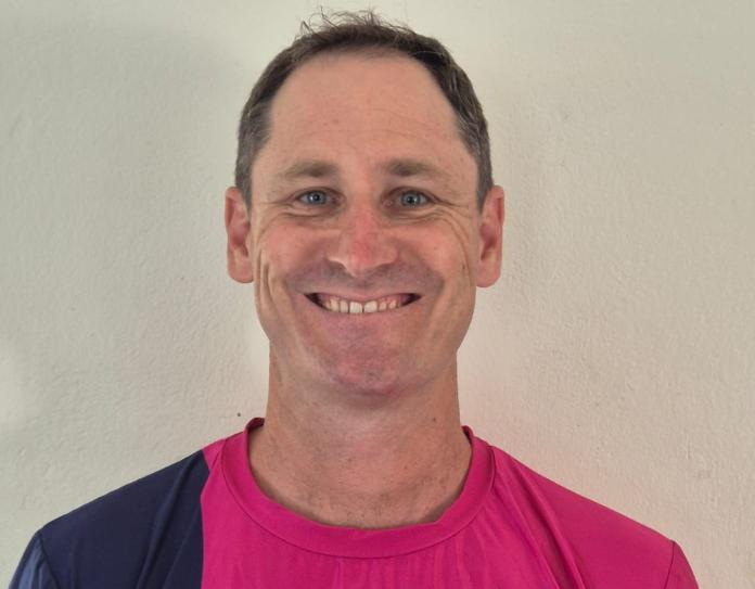 A man wearing a pink T-shirt is smiling