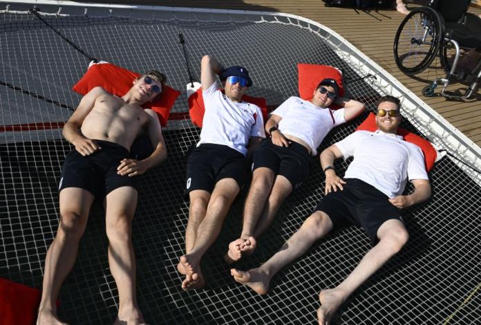 Four male athletes are lying down outside