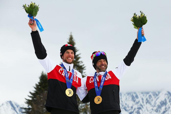 Two Canadian athletes celebrating with a gold medal