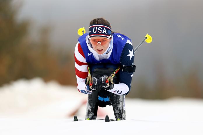 A female sit-skier is competing in a cross-country race