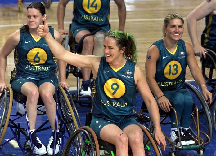 Three wheelchair basketball players are smiling after winning a game