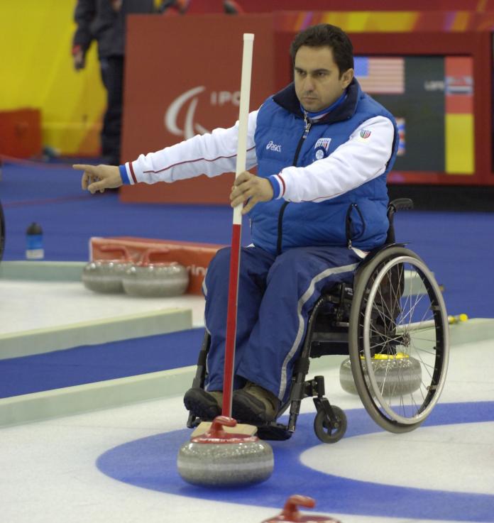 A male wheelchair curling athlete points his right index finger during a competition