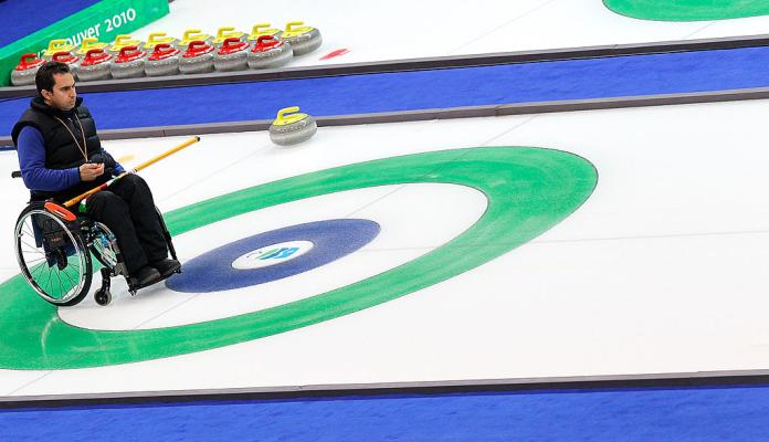 A male wheelchair curling athlete is on the ice during a competition