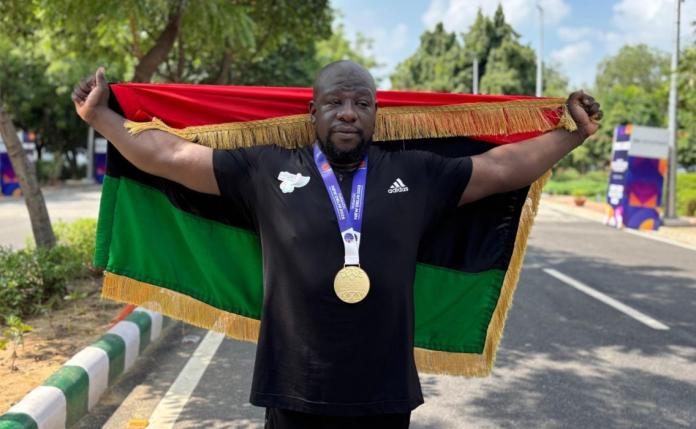 A male athlete wearing a gold medal holds Libya's flag