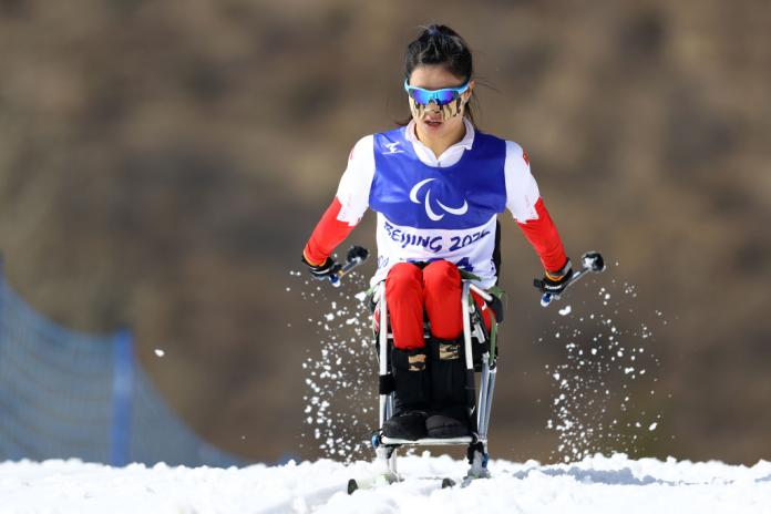 A female cross-country sit-skier is in action.