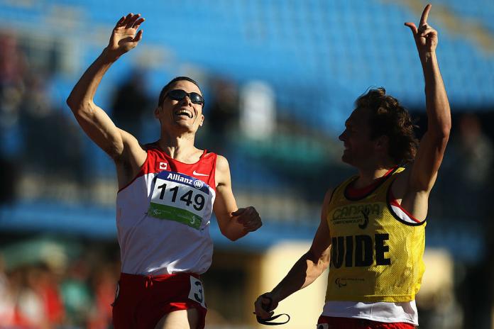 A male Para athlete and his guide are celebrating after winning a race