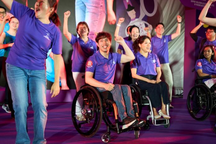 A group of people wearing purple polo shirts are pumping their fists during a party