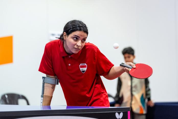 A female Para table tennis player wearing a red shirt in action