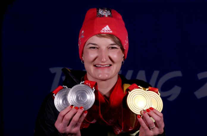 A woman holds up four medals, two silver and two bronze