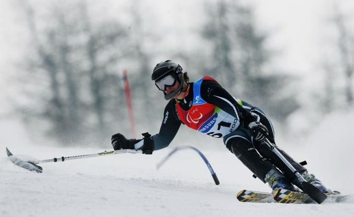 A Para alpine skier making a low turn during competition, while still maintaining balance