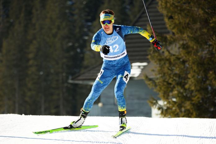A female Para biathlon athlete competing for team Ukraine, while she moves forward towards the finish line.