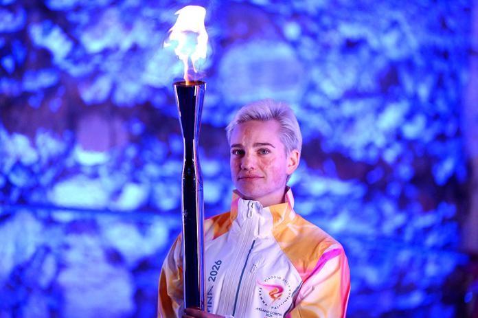 A woman holds the Paralympic torch with flame