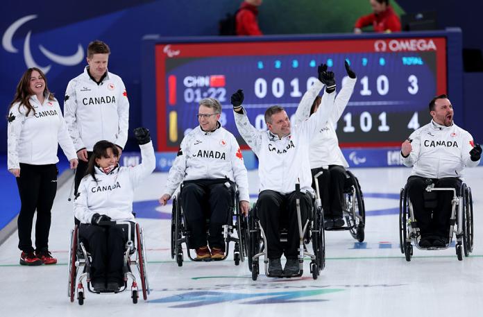 Five male and female curlers in white celebrate