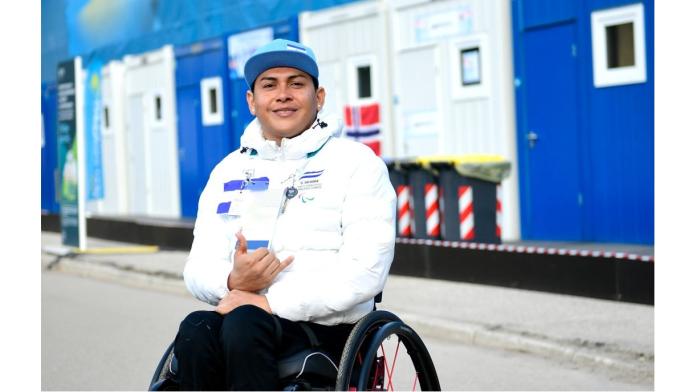 A male Para athlete posing for the picture while doing  a hand loose sign
