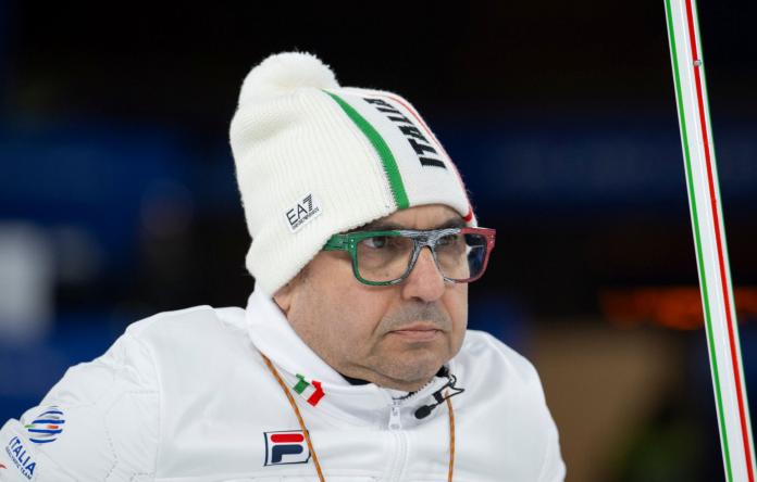 A male athlete wearing a white uniform and a white jersey is wearing glasses with the colours of the Italian flag