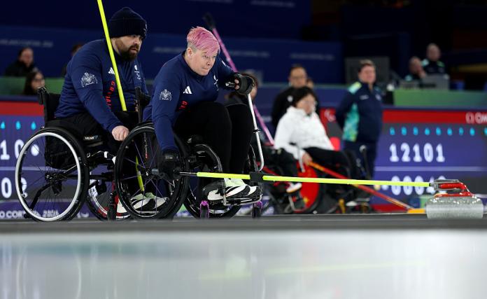 Two wheelchair curlers in action at the Milano Cortina 2026 Paralympic Winter Games