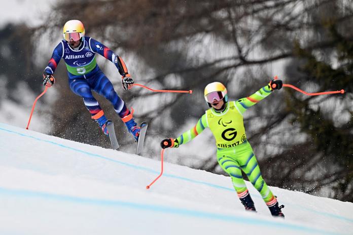 A male Para alpine skier and his guide are in competition
