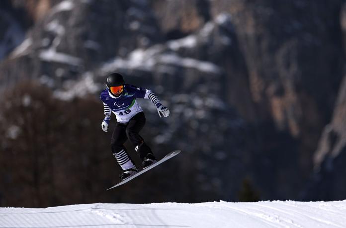 A male Para snowboarder makes a jump during a competition