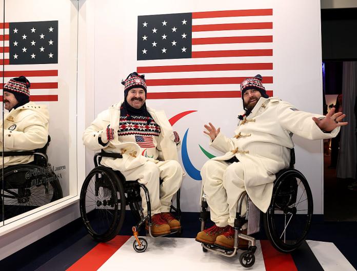 Two male curlers pose in front of the USA flag