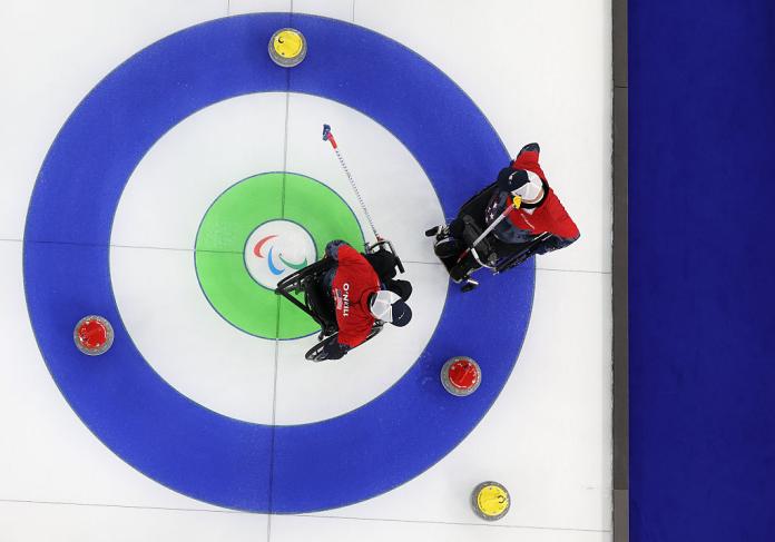 Photo taken from above shows the curling house with four curling stones and two athletes