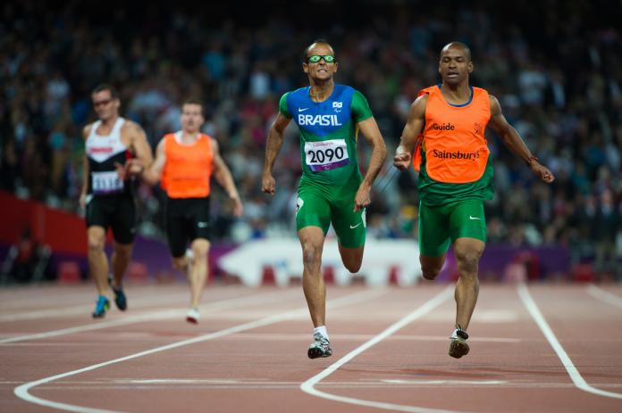 Man and guide sprinting on a stadium track