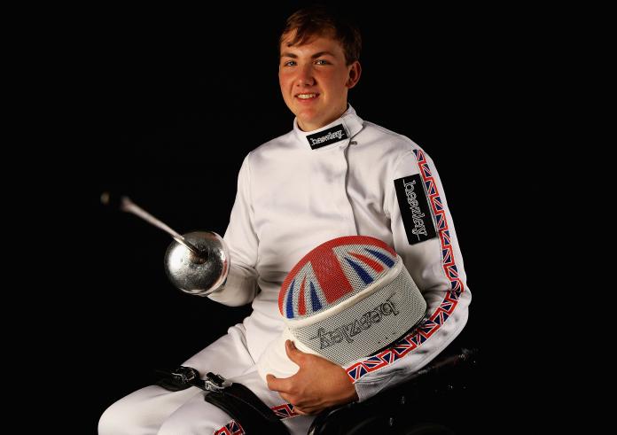 Man in wheelchair with a foil smiling to the camera