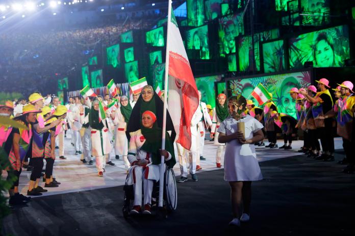 Woman in wheelchair carries Iranian flag during Opening Ceremony