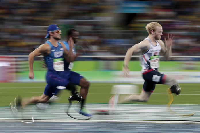 three para sprinters run towards the finish line