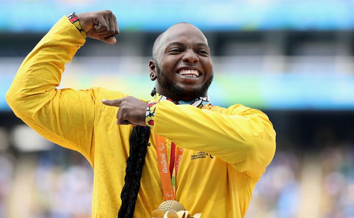 a man holds up his arms in celebration on the podium