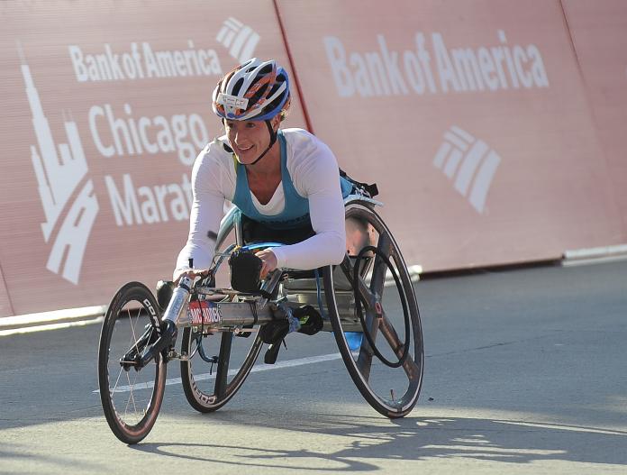 a female wheelchair racer celebrates crossing the line